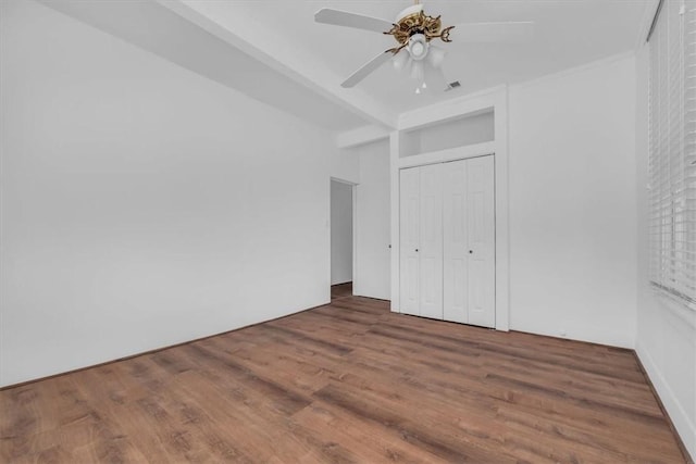 unfurnished bedroom with dark hardwood / wood-style flooring, a closet, and ceiling fan