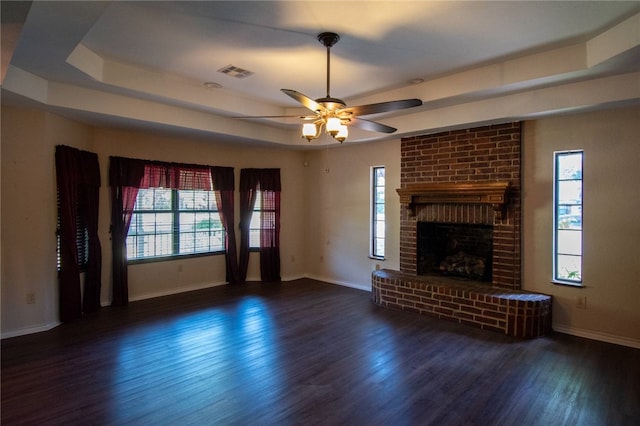 unfurnished living room featuring a healthy amount of sunlight, a brick fireplace, ceiling fan, and dark wood-type flooring