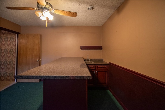 kitchen with ceiling fan, sink, kitchen peninsula, and a textured ceiling