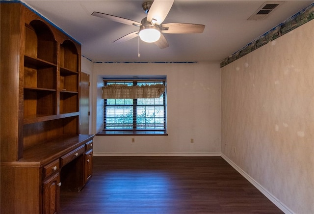 empty room featuring dark hardwood / wood-style flooring, ceiling fan, and built in desk