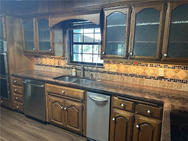 kitchen featuring sink, stainless steel dishwasher, decorative backsplash, dark hardwood / wood-style flooring, and dark brown cabinetry