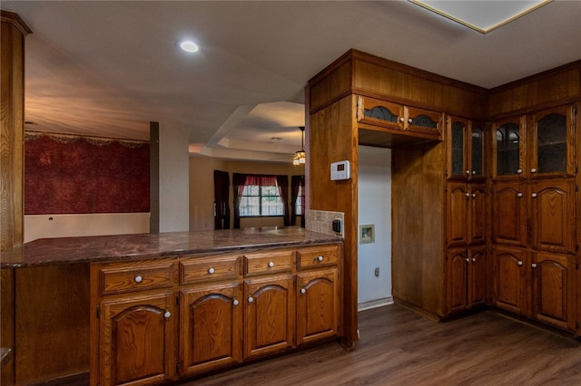 kitchen with dark hardwood / wood-style floors, dark stone countertops, and kitchen peninsula