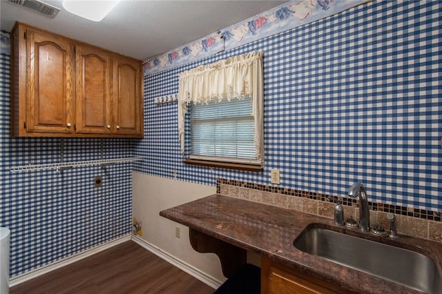 laundry room with a textured ceiling, sink, and dark hardwood / wood-style floors