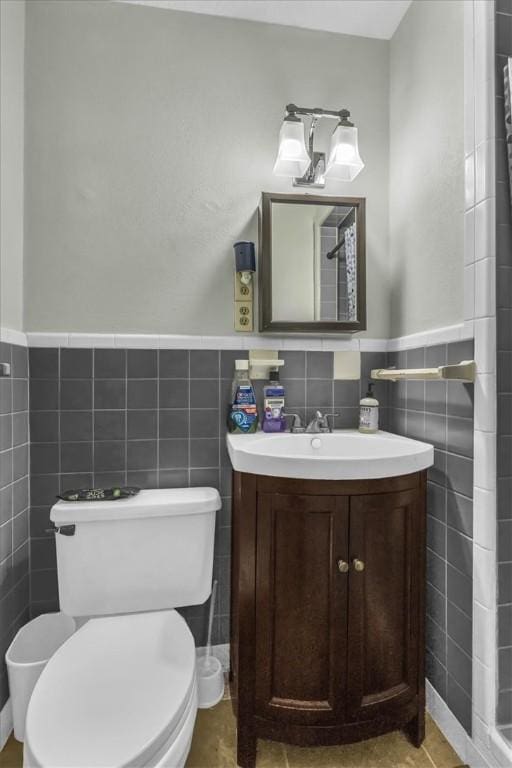 bathroom with tile patterned floors, vanity, toilet, and tile walls