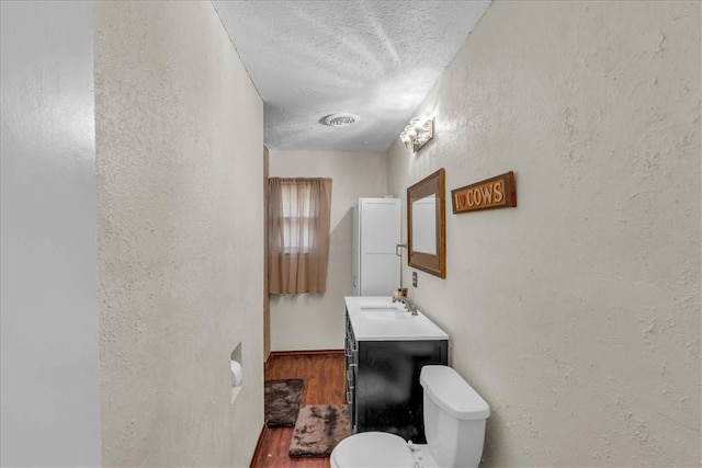 bathroom with toilet, vanity, a textured ceiling, and hardwood / wood-style flooring