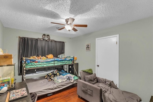 bedroom with ceiling fan, wood-type flooring, and a textured ceiling