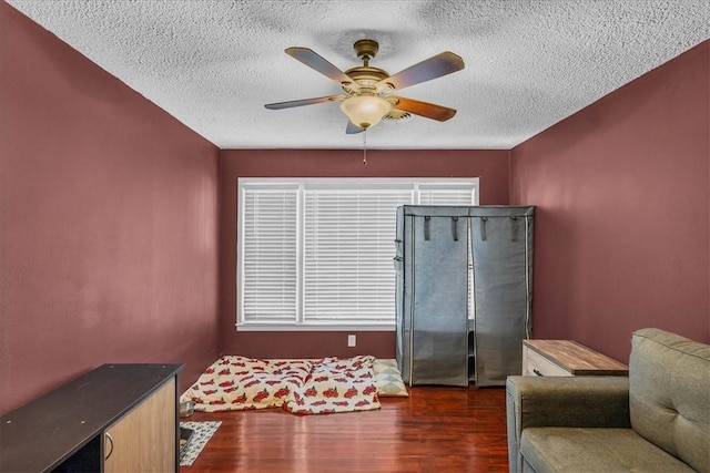 sitting room with a textured ceiling, ceiling fan, and dark wood-type flooring