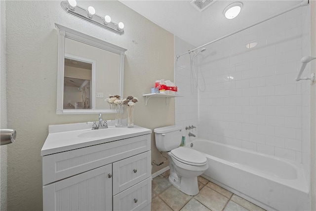 full bathroom with tile patterned floors, vanity, tiled shower / bath, and toilet