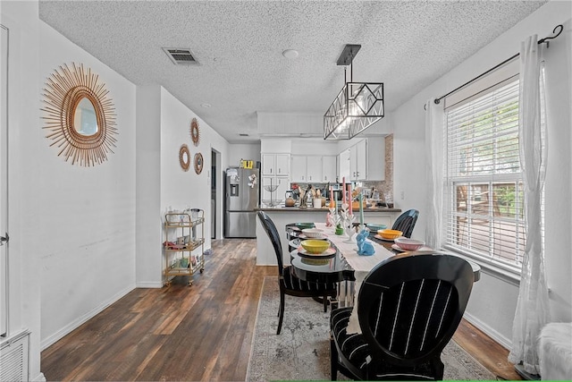 dining room with a textured ceiling and dark wood-type flooring