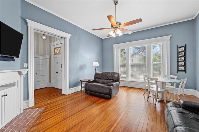 living room featuring ceiling fan, light hardwood / wood-style floors, and crown molding