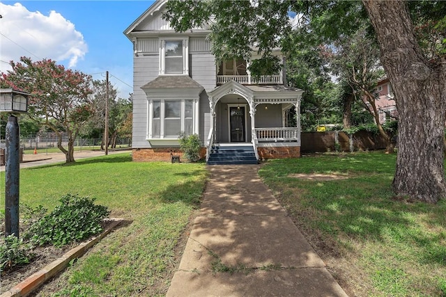 view of front facade featuring a porch, a balcony, and a front yard