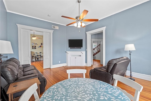 living room with ceiling fan, light wood-type flooring, and ornamental molding