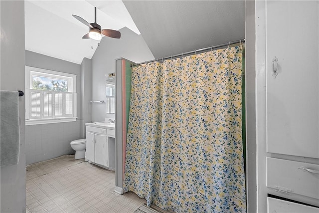 bathroom with vanity, vaulted ceiling, ceiling fan, tile walls, and toilet