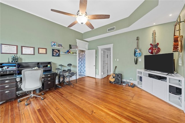 home office with light wood-type flooring and ceiling fan