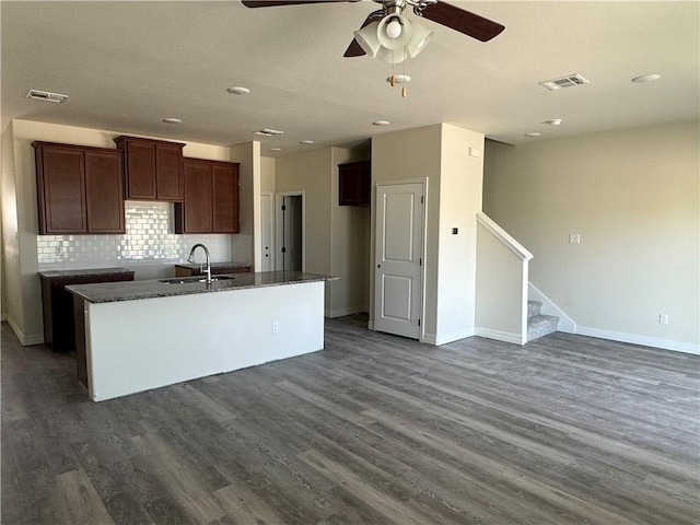 kitchen with decorative backsplash, dark hardwood / wood-style flooring, sink, and a center island with sink