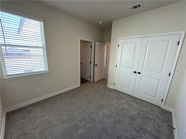 unfurnished bedroom with carpet floors, multiple windows, visible vents, and baseboards