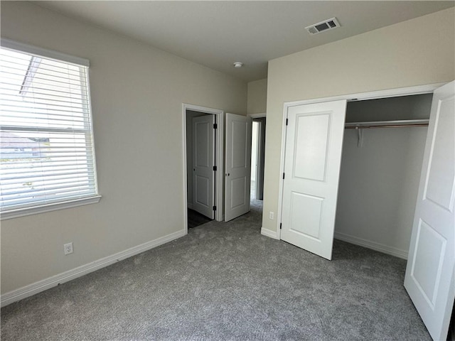 unfurnished bedroom featuring carpet floors, multiple windows, and a closet