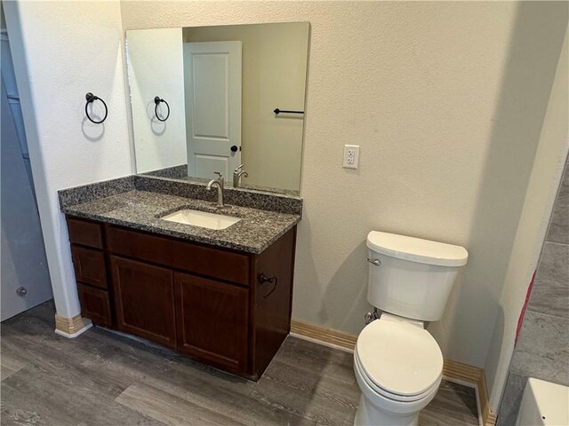 kitchen with a sink, baseboards, light wood finished floors, a center island with sink, and tasteful backsplash