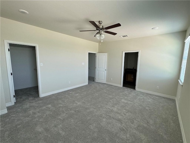 unfurnished bedroom featuring a spacious closet, a closet, carpet floors, and ceiling fan