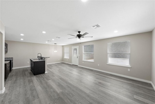 unfurnished living room featuring ceiling fan, sink, and hardwood / wood-style floors