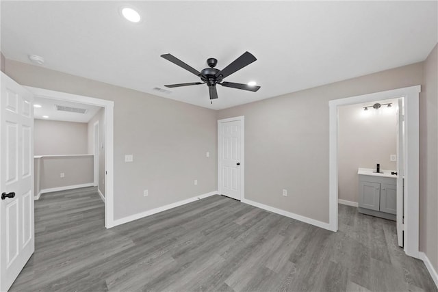 unfurnished bedroom featuring ceiling fan, a closet, ensuite bath, and light hardwood / wood-style flooring