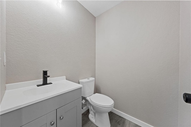 bathroom featuring hardwood / wood-style flooring, vanity, toilet, and vaulted ceiling