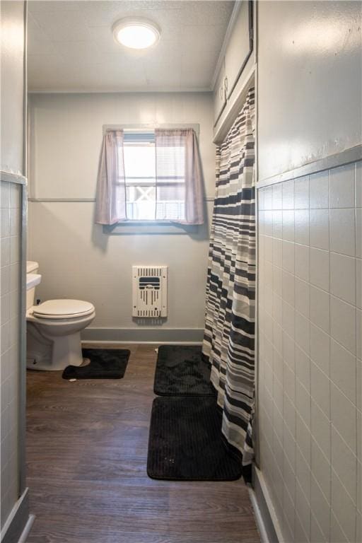 bathroom with hardwood / wood-style floors, toilet, tile walls, curtained shower, and heating unit