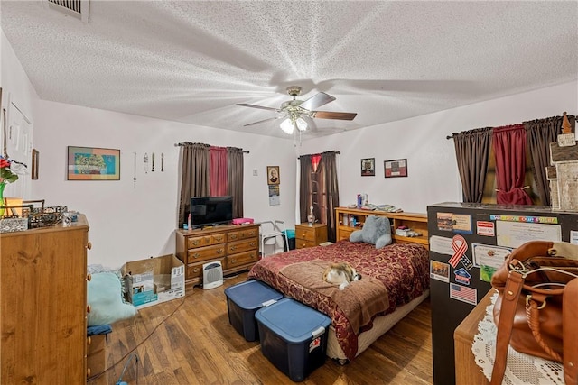 bedroom with hardwood / wood-style floors, a textured ceiling, and ceiling fan