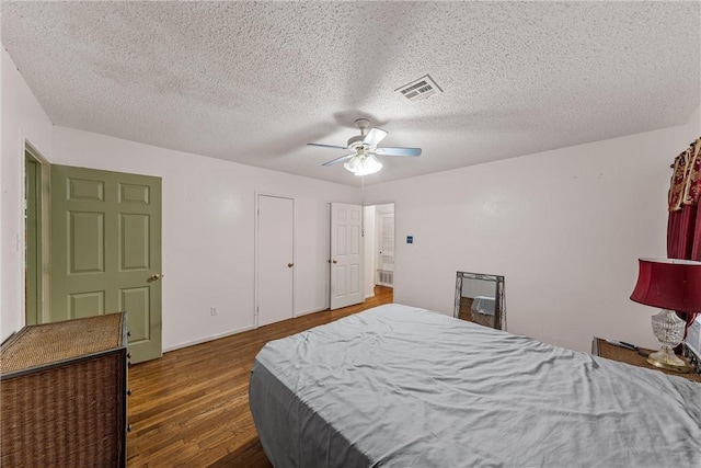 bedroom with ceiling fan, dark hardwood / wood-style flooring, and a textured ceiling