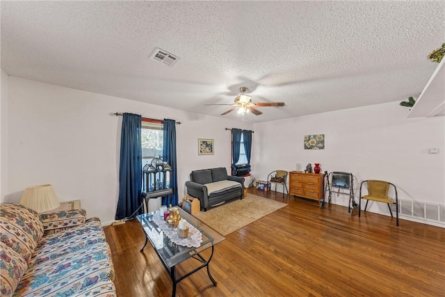 living room with a textured ceiling, hardwood / wood-style flooring, and ceiling fan