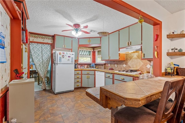 kitchen featuring kitchen peninsula, white appliances, ceiling fan, sink, and tile countertops