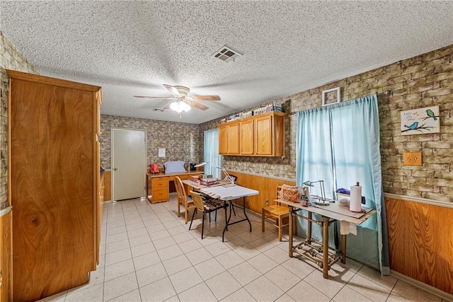 kitchen with a textured ceiling, ceiling fan, and wood walls