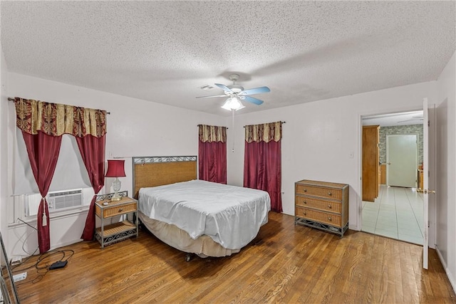 bedroom with ceiling fan, cooling unit, a textured ceiling, and hardwood / wood-style flooring