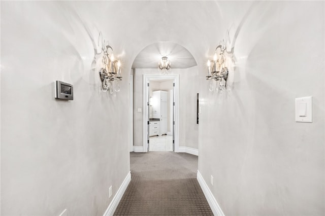 corridor featuring carpet, lofted ceiling, and an inviting chandelier