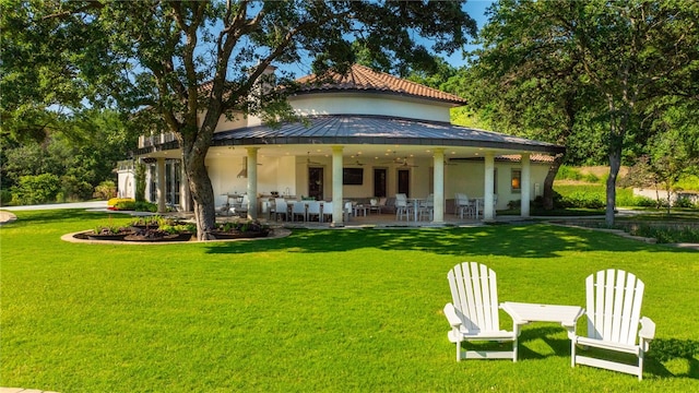 rear view of house with a patio, ceiling fan, and a lawn