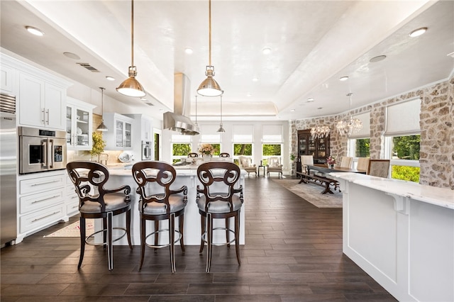 kitchen featuring white cabinets, a wealth of natural light, island range hood, and hanging light fixtures