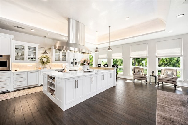 kitchen with a kitchen island with sink, white cabinetry, hanging light fixtures, and extractor fan