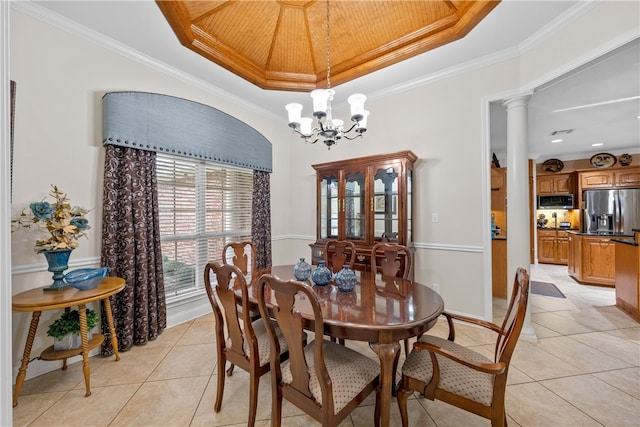 dining room featuring decorative columns, a raised ceiling, crown molding, and a notable chandelier