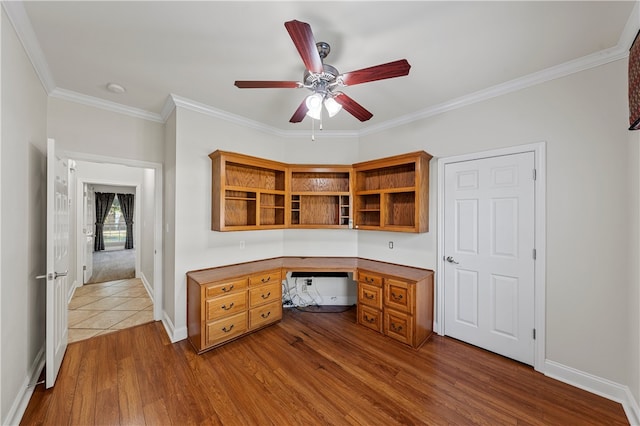 unfurnished office featuring ceiling fan, hardwood / wood-style floors, built in desk, and ornamental molding