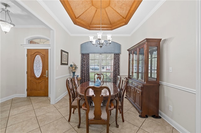 tiled dining room with a chandelier, a tray ceiling, and ornamental molding