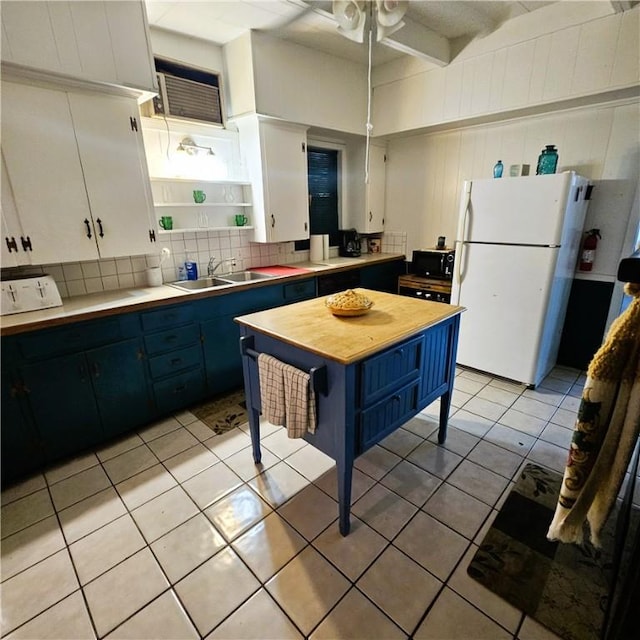 kitchen featuring white fridge, sink, white cabinetry, and blue cabinets