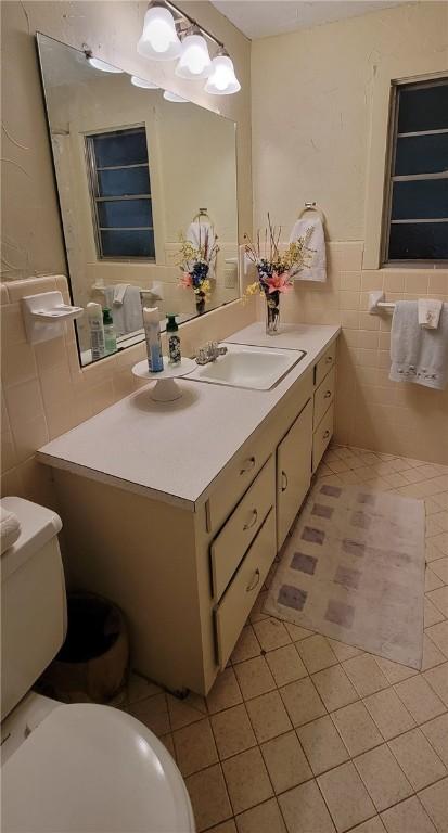 bathroom with tile patterned flooring, vanity, tile walls, and toilet