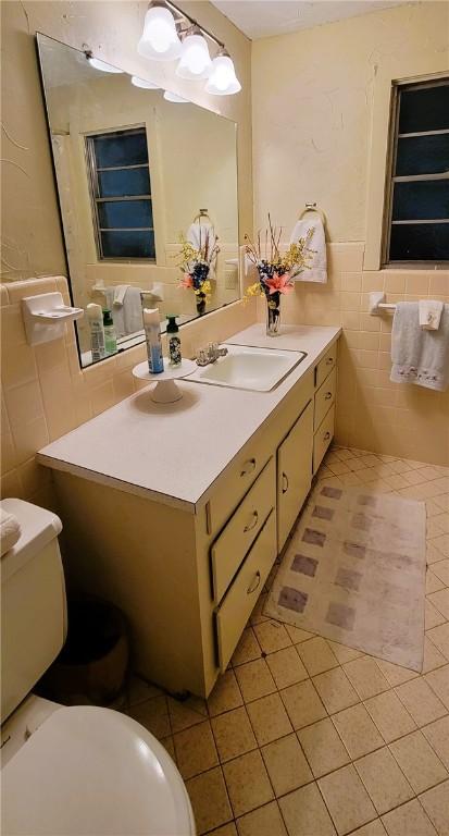 bathroom featuring tile patterned floors, vanity, toilet, and tile walls