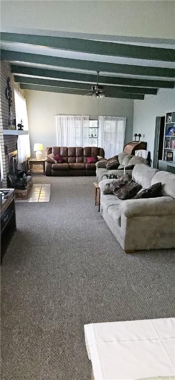 living room featuring beam ceiling, ceiling fan, carpet, and a brick fireplace