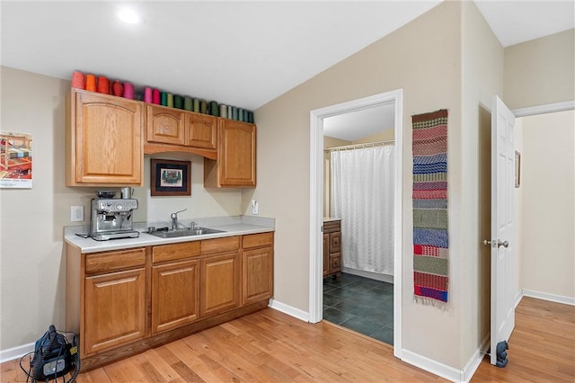 kitchen with lofted ceiling, sink, and light hardwood / wood-style flooring