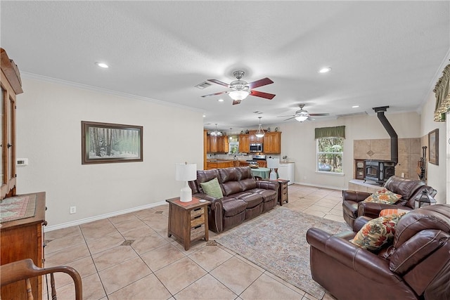 tiled living room with a textured ceiling, a wood stove, ceiling fan, and crown molding