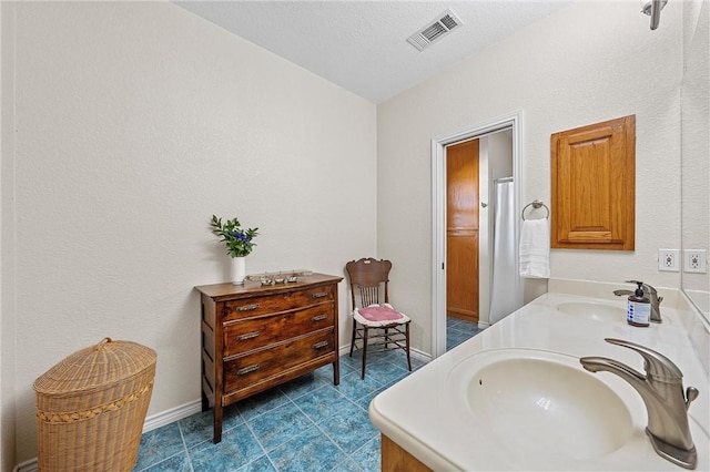 bathroom with tile patterned flooring, vanity, and a textured ceiling