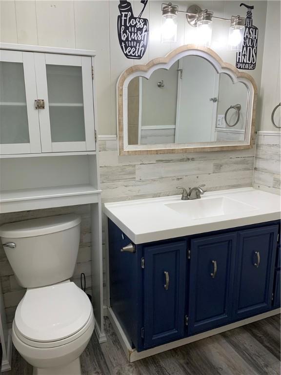 bathroom with toilet, vanity, and wood-type flooring