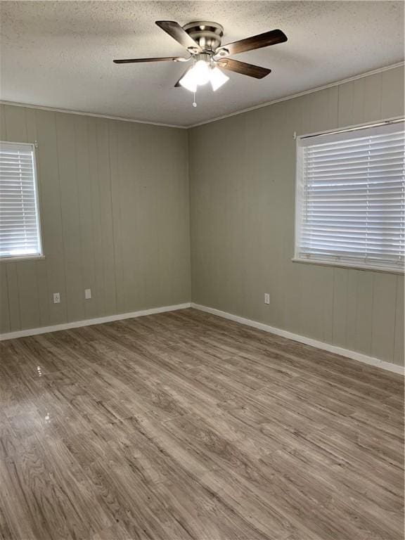 unfurnished room with a textured ceiling, ceiling fan, a wealth of natural light, and hardwood / wood-style floors