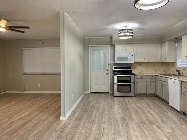 kitchen with sink, white appliances, light hardwood / wood-style flooring, a textured ceiling, and white cabinets